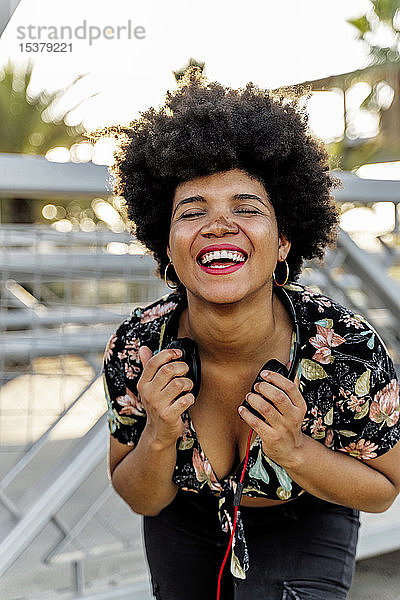Porträt einer lachenden Afroamerikanerin mit Kopfhörern