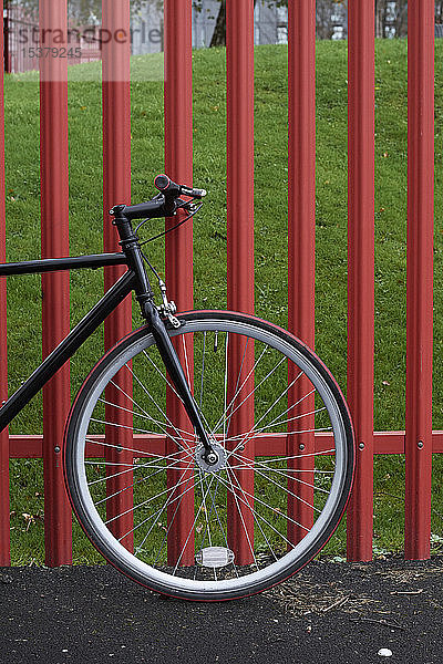 Fahrrad an der Straße durch Zaun im Park geparkt