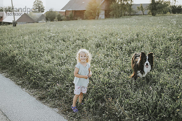 Mädchen geht mit Hund auf dem Land spazieren