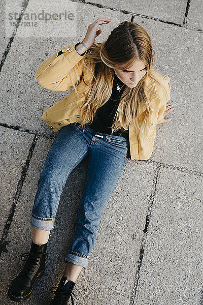 Junge Frau in gelber Jacke auf dem Boden sitzend