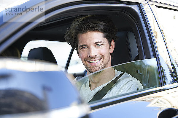 Porträt eines lächelnden Mannes beim Autofahren
