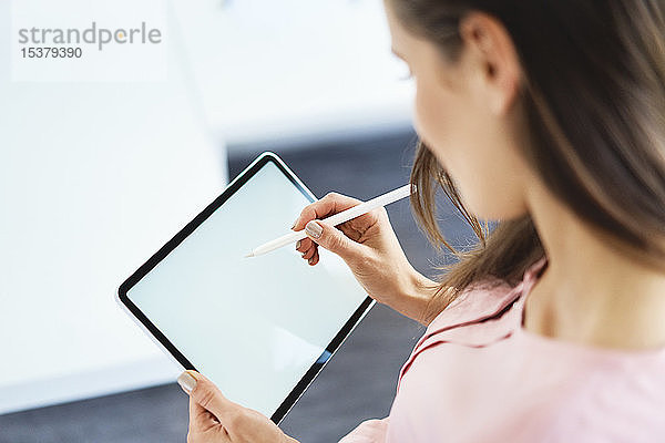 Über-die-Schulter-Ansicht einer Frau  die mit Bleistift auf einem Tablett zeichnet