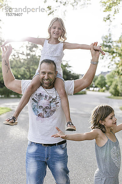 Vater trägt glückliche Tochter auf seinen Schultern
