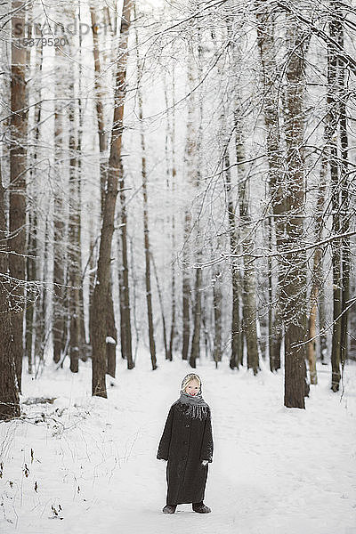 Lächelndes kleines Mädchen steht vor dem Winterwald