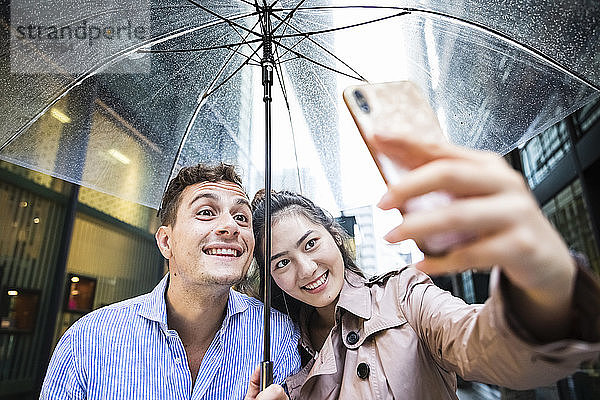 Glückliches Paar mit Regenschirm beim Selfie in Ginza  Tokio  Japan