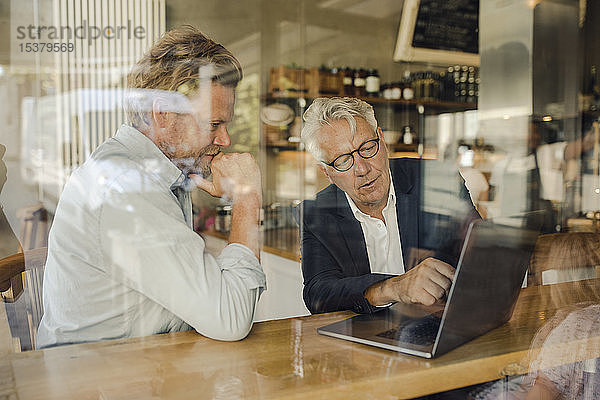 Zwei Geschäftsleute mit Laptop treffen sich in einem Cafe