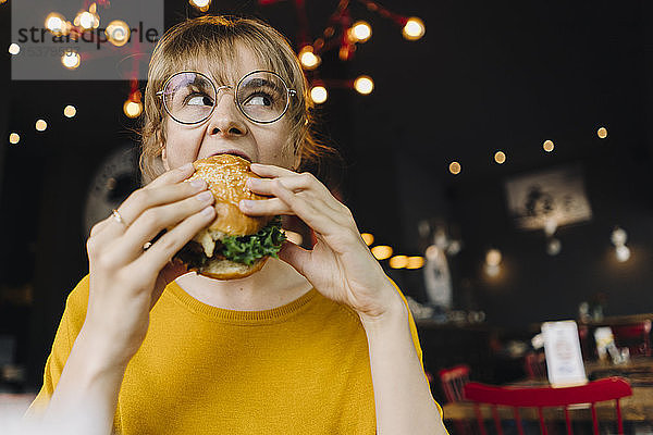 Junge Frau isst Burger in einem Restaurant