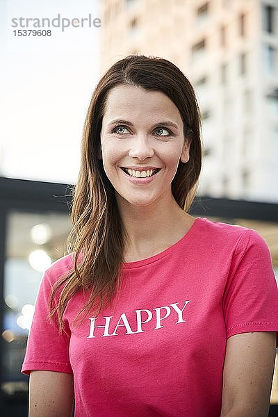 Porträt einer glücklichen Frau mit rosa T-Shirt in der Stadt