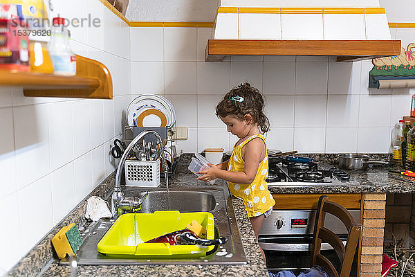 Kleines Mädchen  das zu Hause in der Küche Geschirr spült