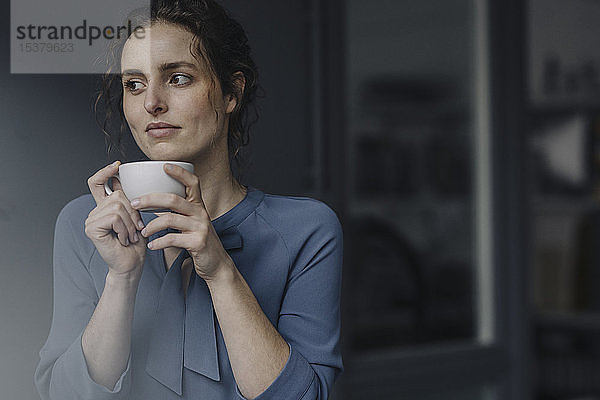 Porträt einer jungen Frau  die sich bei einer Tasse Kaffee entspannt