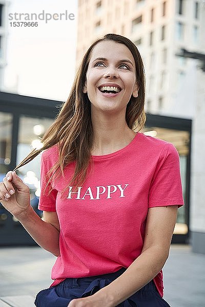 Porträt einer lachenden Frau mit rosa T-Shirt in der Stadt