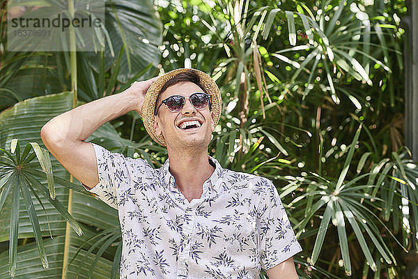 Lächelnder Mann mit Hut und Sonnenbrille in einem Park