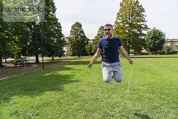 Glücklicher Mann springt Seil in einem Park