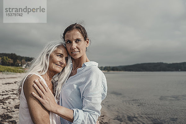 Mutter und Tochter verbringen einen Tag am Meer  umarmen sich am Strand