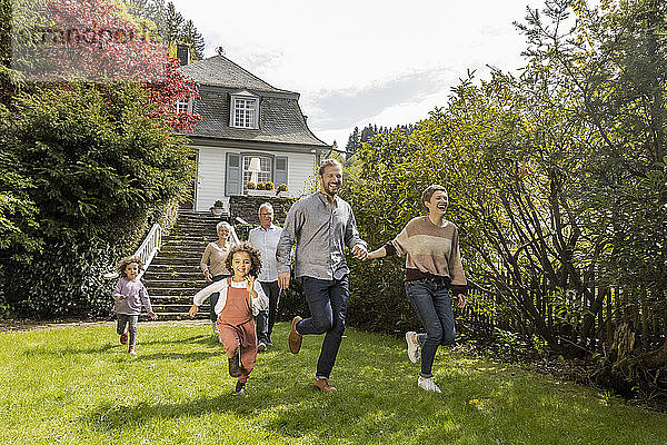 Glückliche Großfamilie läuft im Garten ihres Hauses