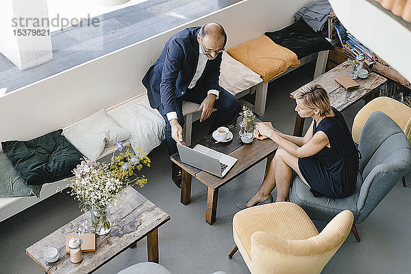 Ein Geschäftsmann und eine Geschäftsfrau treffen sich in einem Café und diskutieren über die Arbeit