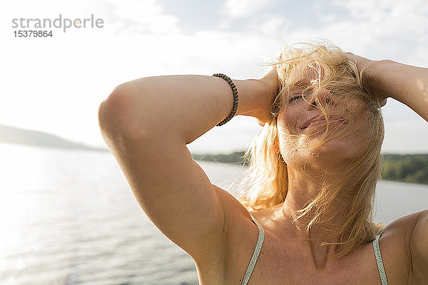 Junge Frau mit windgepeitschtem Haar an einem See
