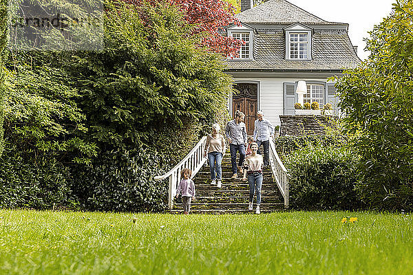 Großfamilie  die auf einer Treppe im Garten ihres Hauses geht