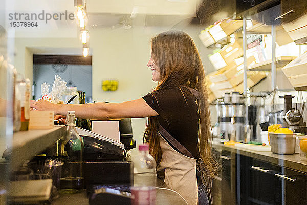 Junge Frau  die am Tresen eines Cafés arbeitet