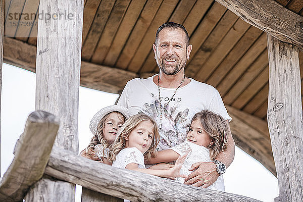 Glücklicher Vater mit drei Drillingsschwestern in einem Baumhaus