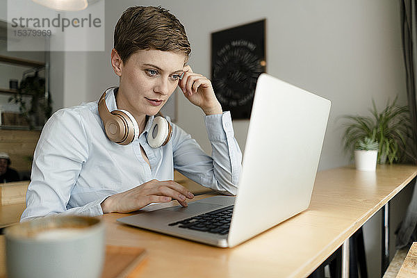 Geschäftsfrau mit Kopfhörern mit Laptop in einem Café