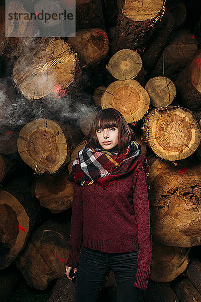 Porträt einer jungen Frau am Holzstapel