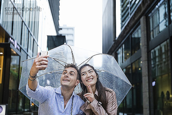 Glückliches Paar mit Regenschirm beim Selfie in Ginza  Tokio  Japan