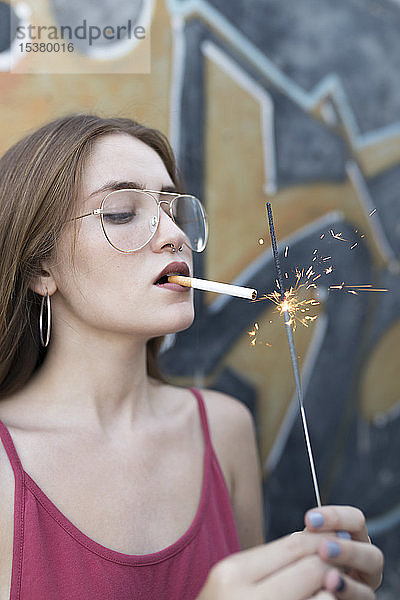 junge Frau zündet Zigarette mit einer Wunderkerze an
