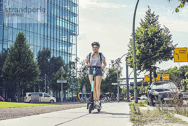 Junge Frau fährt E-Scooter auf Bürgersteig  Berlin  Deutschland