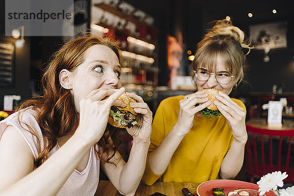 Zwei Freundinnen essen Burger in einem Restaurant
