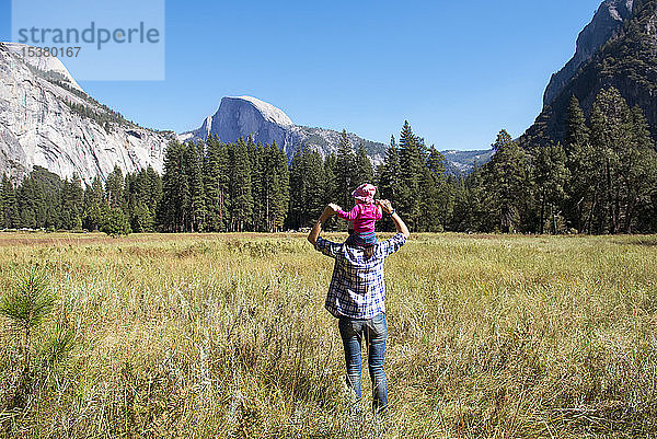 Rückenansicht eines Vaters  der seine kleine Tochter auf den Schultern trägt  Yosemite National Park  Kalifornien  USA