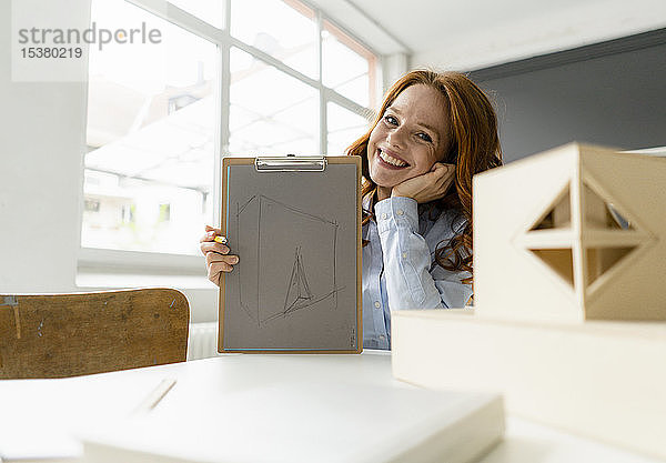 Porträt einer rothaarigen Frau mit Zeichnung und Architekturmodell in einem Loft