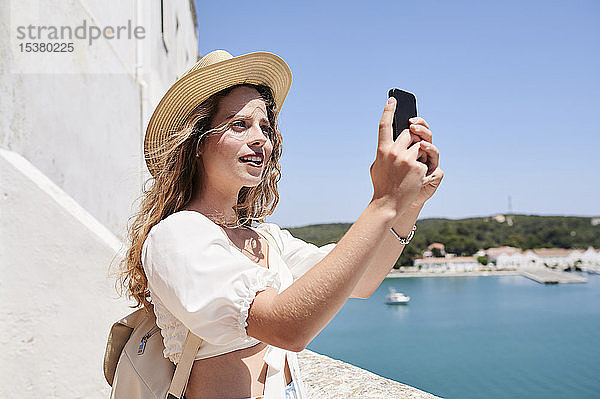 Junge Frau beim Selfie an der Küste  Menorca  Spanien