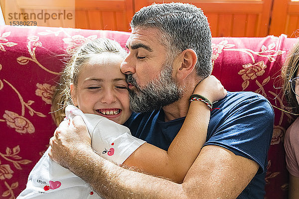 Vater umarmt mit Tochter zu Hause auf der Couch