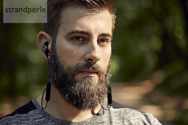Porträt eines sportlichen Mannes mit Kopfhörern im Wald