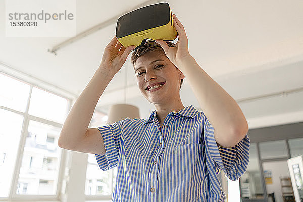 Porträt einer lächelnden Geschäftsfrau mit VR-Brille im Büro