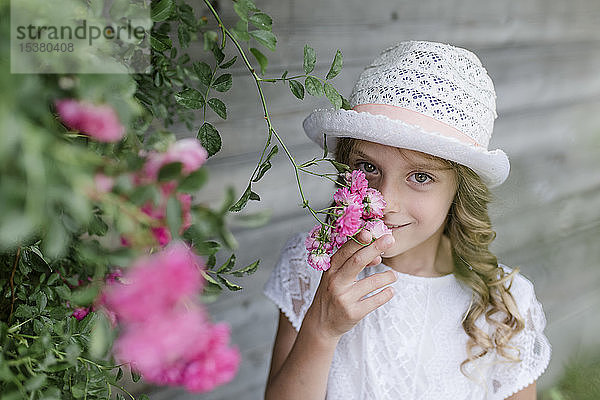 Porträt eines Mädchens am blühenden Rosenbusch