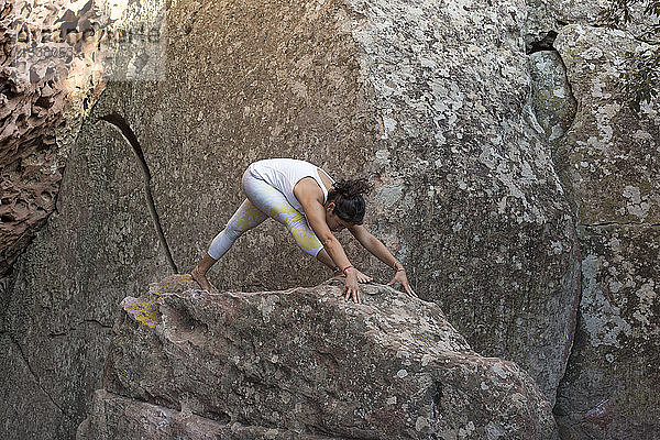 Junge Asiatin praktiziert Yoga auf einem Felsen