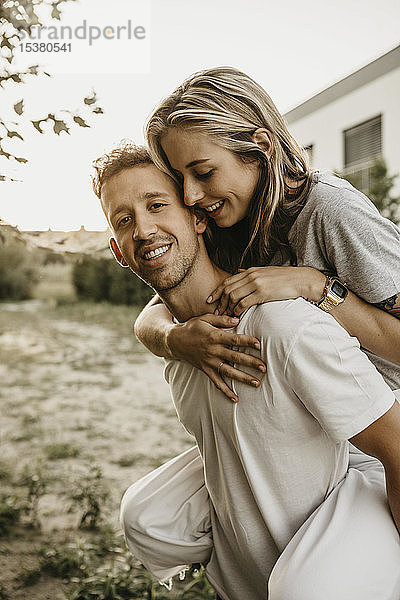 Porträt eines jungen lächelnden Paares  Mann trägt Frau auf dem Rücken