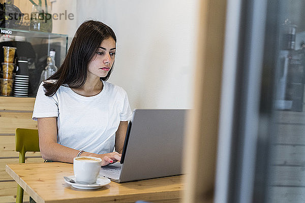 Junge Frau mit Laptop in einem Café