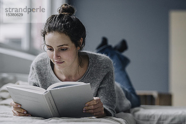 Porträt einer jungen Frau  die zu Hause ein Buch liest