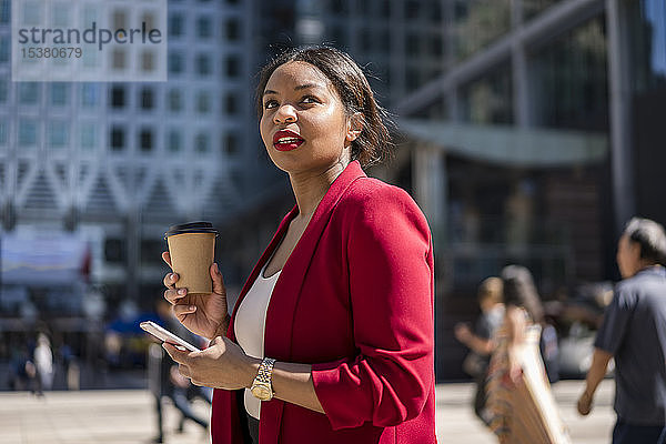 Porträt einer Geschäftsfrau mit Kaffee zum Mitnehmen und Handy  London  UK