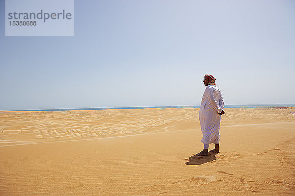 Beduine in Nationaltracht in der Wüste stehend  Rückansicht  Wahiba Sands  Oman