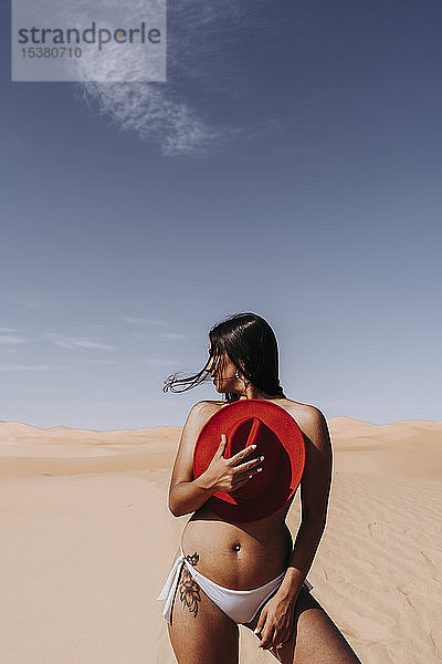 Sexy junge Frau mit Bikinihose und Hut in der Wüste  Merzouga  Marokko