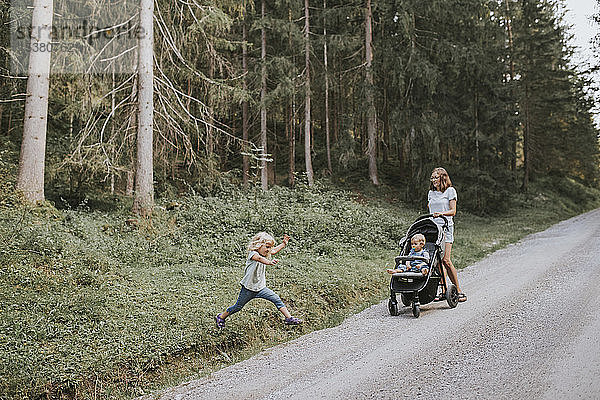 Mutter mit Tochter und Baby im Kinderwagen im Wald