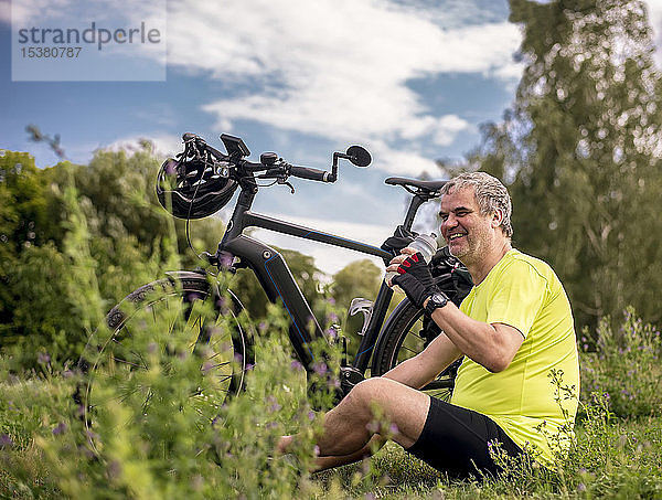 Glücklicher reifer Mann macht eine Pause während seiner Fahrradtour mit einem E-Bike