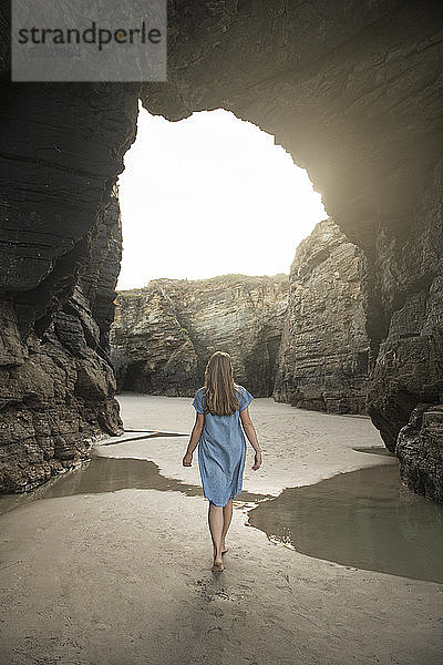 Frau beim Spaziergang am Strand der Kathedralen mit Felsen  Rückansicht  Galicien  Spanien