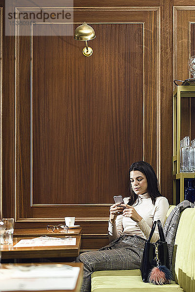 Geschäftsfrau benutzt Mobiltelefon in einem Restaurant