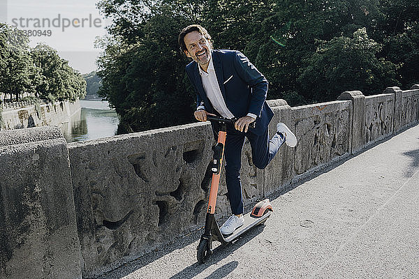 Geschäftsmann mit E-Scooter auf einer Brücke