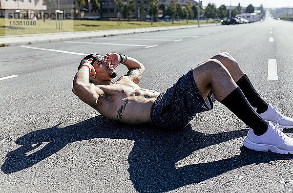 Junger Mann macht Sit-ups auf einer Straße